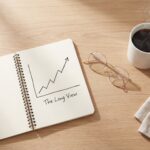 Overhead view of a clean desk with a notebook and coffee, representing deep analysis of Australian economic data.