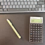 A financial calculator and pen on Daniel Nel's desk, with part of a keyboard above.